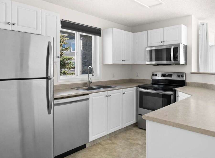 Discover this charming kitchen featuring sleek stainless steel appliances, including a refrigerator, dishwasher, and microwave.