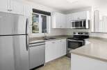 Discover this charming kitchen featuring sleek stainless steel appliances, including a refrigerator, dishwasher, and microwave.