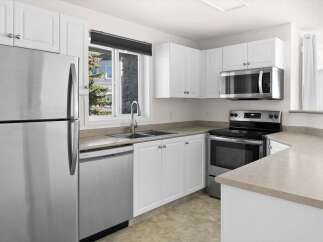 Discover this charming kitchen featuring sleek stainless steel appliances, including a refrigerator, dishwasher, and microwave.