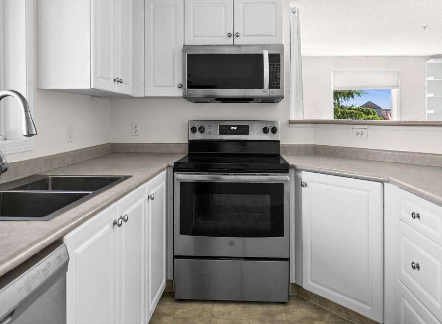 Discover this charming kitchen featuring sleek stainless steel appliances, including a modern microwave and a spacious oven.