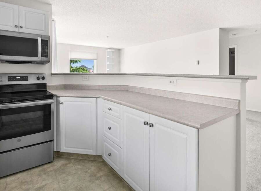 Discover this charming kitchen featuring sleek stainless steel appliances, including a microwave and oven, complemented by crisp white cabinetry.