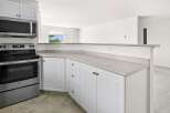 Discover this charming kitchen featuring sleek stainless steel appliances, including a microwave and oven, complemented by crisp white cabinetry.