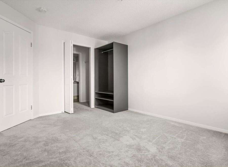 Discover this spacious bedroom featuring a modern gray open closet with shelving and a hanging rod, perfect for organizing your wardrobe.