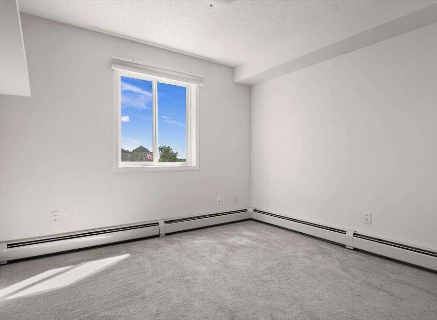 This spacious room features a large window offering abundant natural light and a view of the outdoors.