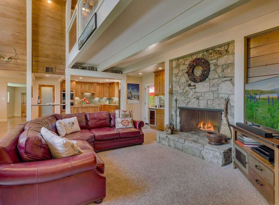 Experience rustic charm in this spacious living area, featuring a grand stone fireplace and a soaring wood-paneled ceiling.