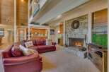 Experience rustic charm in this spacious living area, featuring a grand stone fireplace and a soaring wood-paneled ceiling.