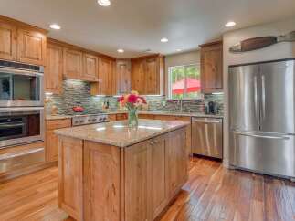 This spacious kitchen boasts beautiful natural wood cabinetry and a large granite-topped island, perfect for meal preparation and casual dining.