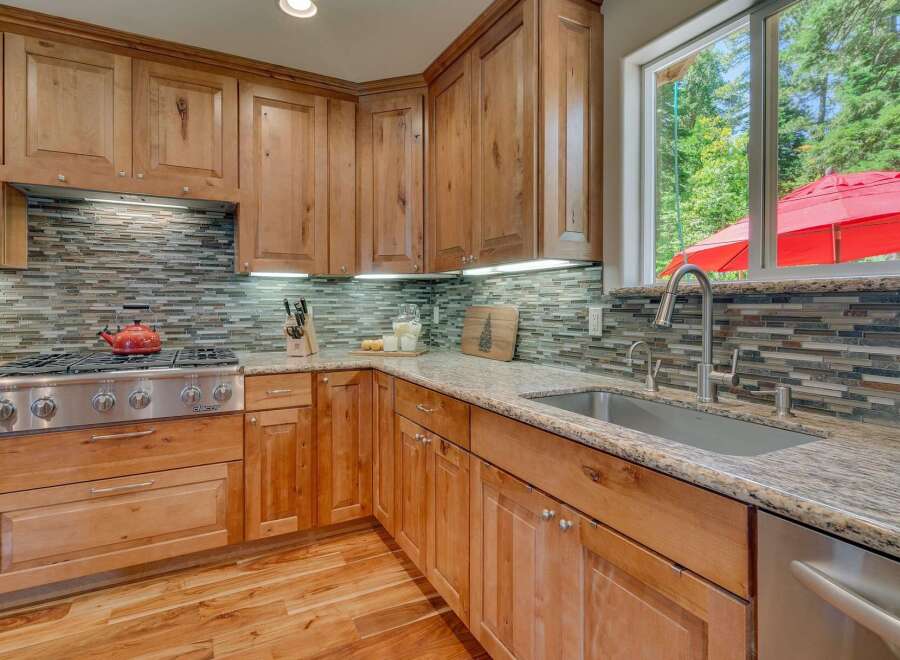 This beautifully appointed kitchen features custom wood cabinetry and a stunning mosaic tile backsplash.