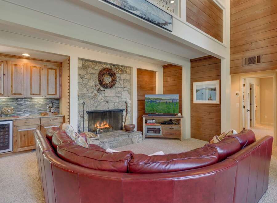 Experience ultimate relaxation in this stunning living room, featuring a cozy stone fireplace and a luxurious curved leather sofa perfect for gathering.