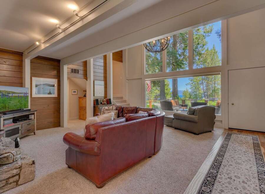 Experience breathtaking lake and mountain views from this stunning living room, featuring a massive floor-to-ceiling window that floods the space with natural light.