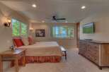 Experience breathtaking lake views from this serene bedroom, featuring a comfortable bed adorned with striped linens and decorative pillows.