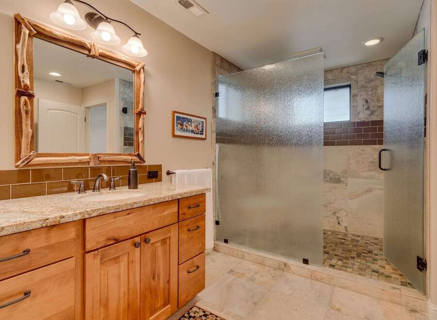 This luxurious bathroom features a spacious walk-in shower with frosted glass doors and elegant tilework.