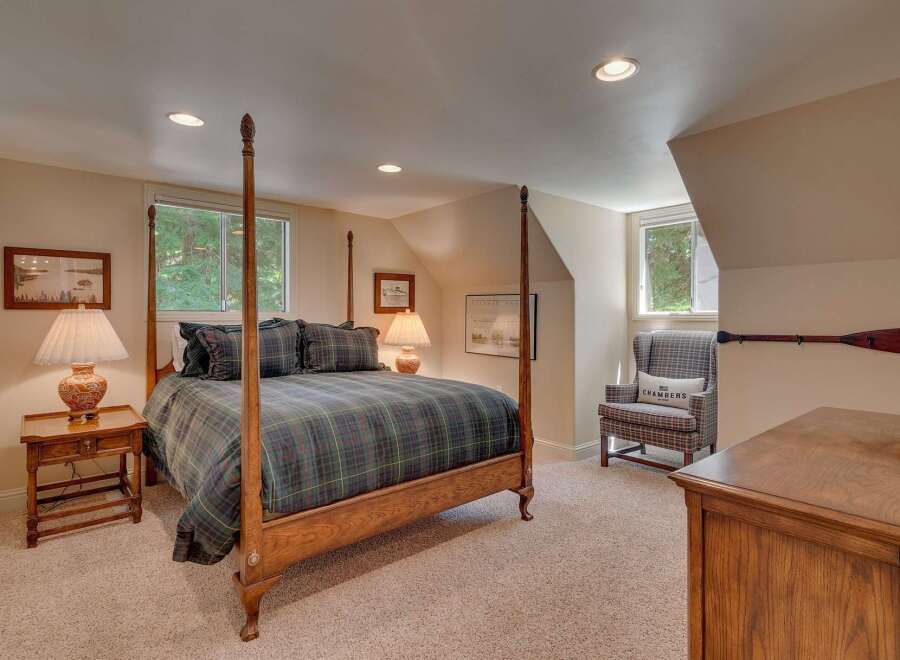 Experience rustic charm in this cozy bedroom featuring a classic four-poster bed dressed in a timeless plaid comforter.