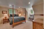 Experience rustic charm in this cozy bedroom featuring a classic four-poster bed dressed in a timeless plaid comforter.