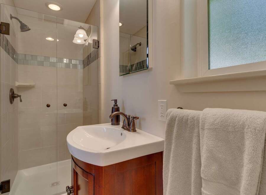 This charming bathroom features a modern glass-enclosed shower with elegant tile work and bronze fixtures.
