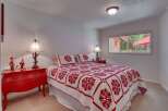 This charming bedroom features a cozy queen-size bed adorned with a striking red and white floral quilt and matching pillows.
