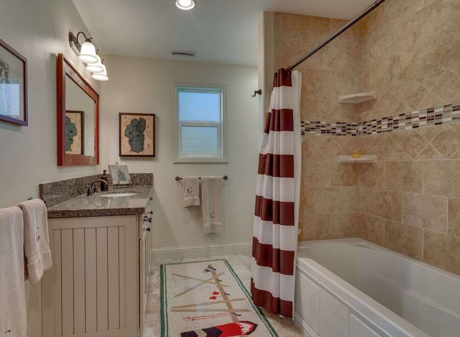 This charming bathroom features a spacious vanity with a granite countertop and a decorative tiled backsplash.