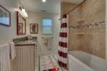 This charming bathroom features a spacious vanity with a granite countertop and a decorative tiled backsplash.