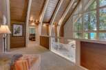 This stunning lakefront property boasts a unique architectural design with a vaulted wood-paneled ceiling and expansive windows offering breathtaking water views.