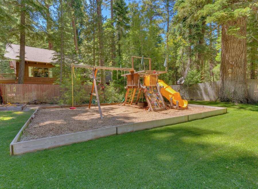 Enjoy endless family fun in this spacious backyard, complete with a vibrant playground featuring swings, a climbing wall, and a thrilling yellow slide.