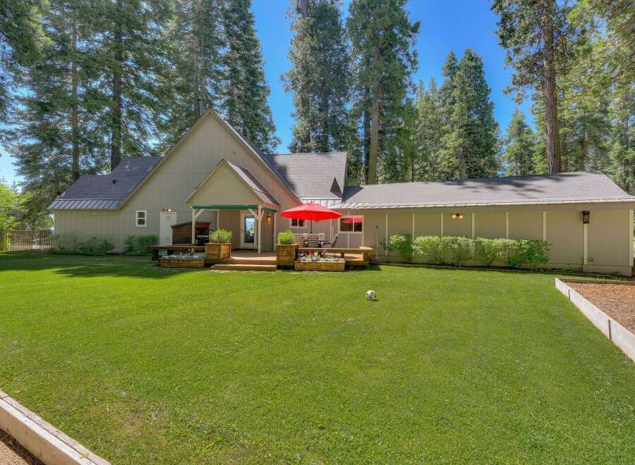 Nestled among towering trees, this charming home offers a serene retreat with a spacious backyard perfect for outdoor living.