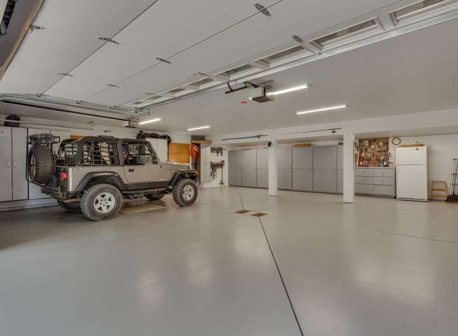 This spacious garage offers ample storage with multiple cabinets and a workbench area, perfect for any hobbyist or car enthusiast.