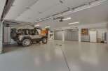 This spacious garage offers ample storage with multiple cabinets and a workbench area, perfect for any hobbyist or car enthusiast.