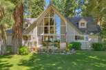 Experience breathtaking lake views from this stunning A-frame home, featuring a grand wall of windows that floods the living space with natural light.