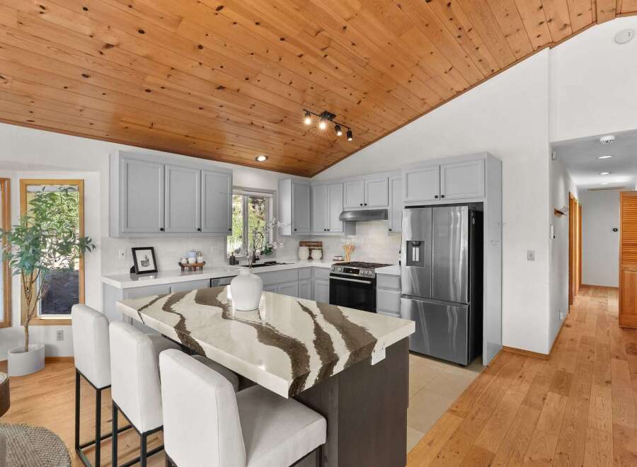 Experience the charm of this beautifully updated kitchen, featuring a striking island with a unique stone countertop and comfortable bar seating.