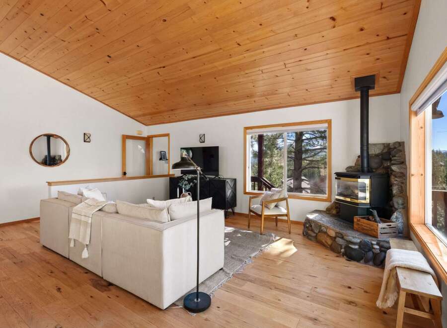 Experience cozy living in this charming mountain retreat, featuring a stunning wood-paneled ceiling and a prominent stone-clad fireplace perfect for chilly evenings.