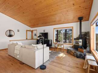 Experience cozy living in this charming mountain retreat, featuring a stunning wood-paneled ceiling and a prominent stone-clad fireplace perfect for chilly evenings.
