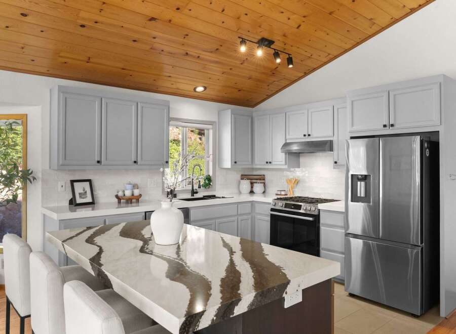 Experience modern living in this stunning kitchen, featuring sleek grey cabinetry and a striking quartz island with a unique, flowing pattern.