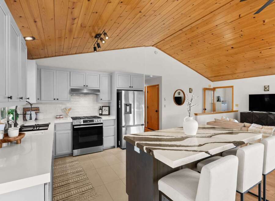 Experience modern living in this stunning kitchen featuring sleek grey cabinetry and a striking quartz island with waterfall edges.