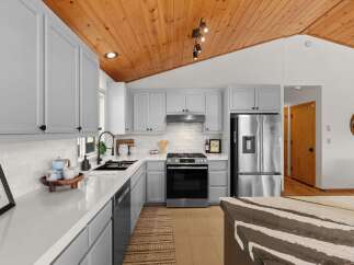 This stunning kitchen boasts sleek, light gray cabinetry complemented by a durable white quartz countertop.