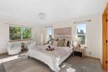 Experience serene living in this beautifully appointed bedroom, featuring a plush king-sized bed adorned with decorative pillows and a cozy throw.