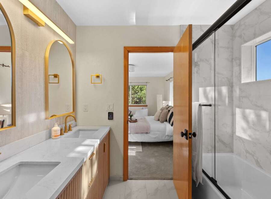 Experience modern luxury in this stunning bathroom featuring a dual vanity with elegant gold fixtures and a sleek marble shower.
