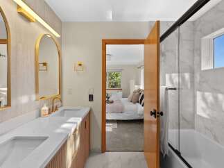 Experience modern luxury in this stunning bathroom featuring a dual vanity with elegant gold fixtures and a sleek marble shower.