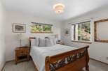 Experience serene living in this charming bedroom, featuring a beautiful wooden sleigh bed and large windows that offer picturesque views of the surrounding natural landscape.
