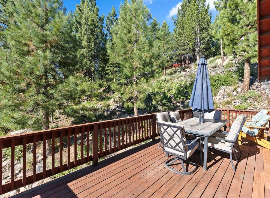 Enjoy outdoor living on this spacious wooden deck, perfect for entertaining or relaxing amidst a serene natural setting.