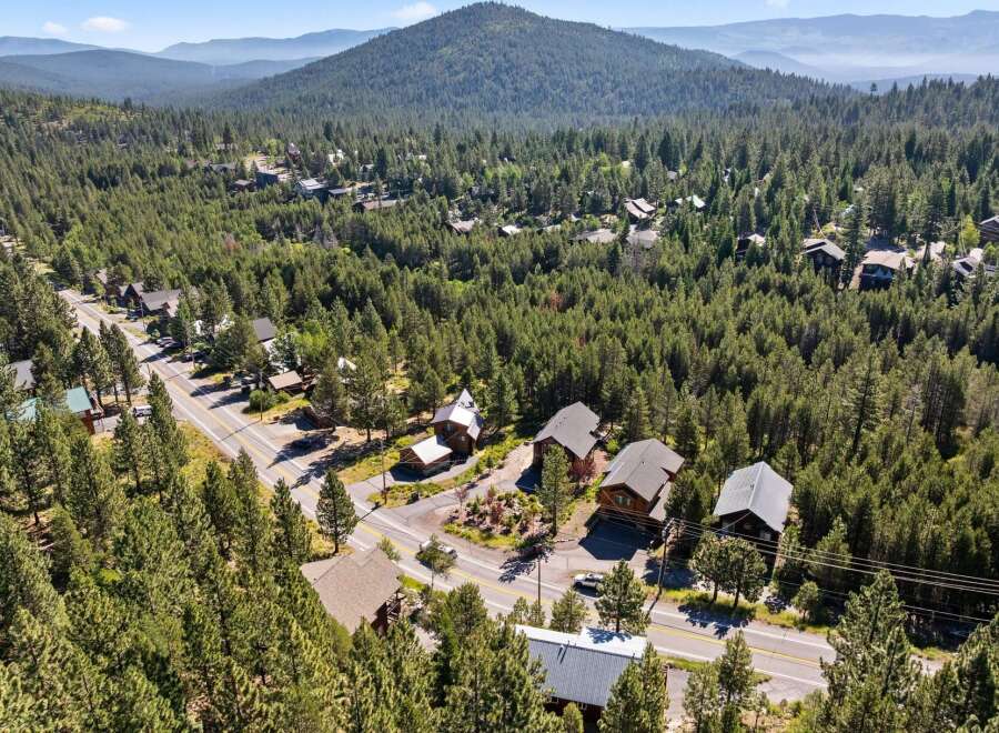 Nestled amidst a dense forest, this property offers a serene mountain retreat with multiple homes surrounded by towering pine trees.