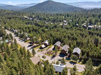 Nestled amidst a dense forest, this property offers a serene mountain retreat with multiple homes surrounded by towering pine trees.