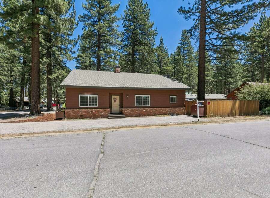 Charming single-story home nestled among tall pine trees, offering a serene and private setting.
