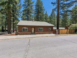 Charming single-story home nestled among tall pine trees, offering a serene and private setting.
