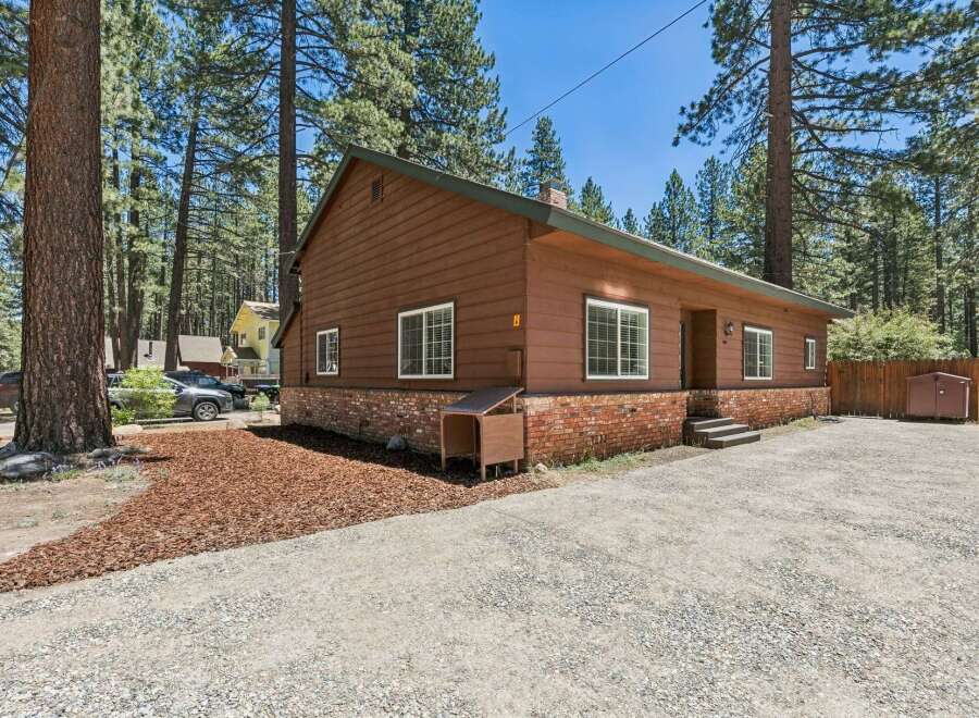 Nestled among tall pine trees, this charming brown home offers a serene retreat.