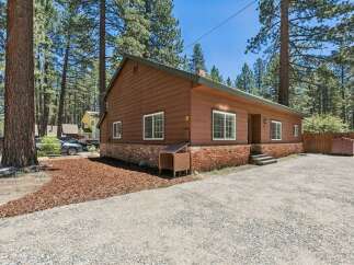 Nestled among tall pine trees, this charming brown home offers a serene retreat.
