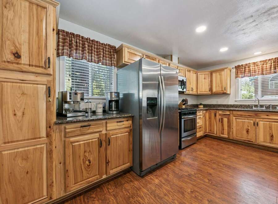 This spacious kitchen boasts beautiful natural wood cabinetry and granite countertops, offering a warm and inviting atmosphere.