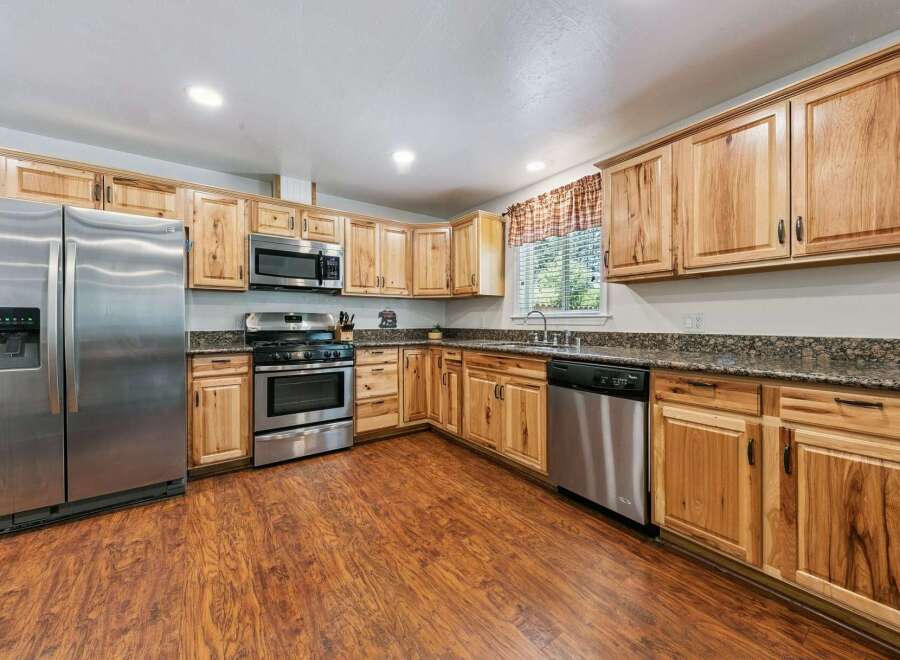 This spacious kitchen boasts beautiful natural wood cabinetry and granite countertops, offering a warm and inviting atmosphere.