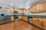 This spacious kitchen boasts beautiful natural wood cabinetry and granite countertops, offering a warm and inviting atmosphere.