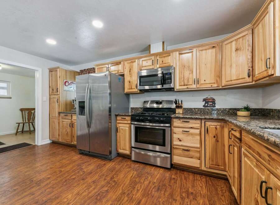 Discover this charming kitchen featuring warm, natural wood cabinetry that extends to the ceiling, offering ample storage.