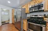 This kitchen features a spacious stainless steel refrigerator, a gas range with a microwave above, and ample natural wood cabinetry.